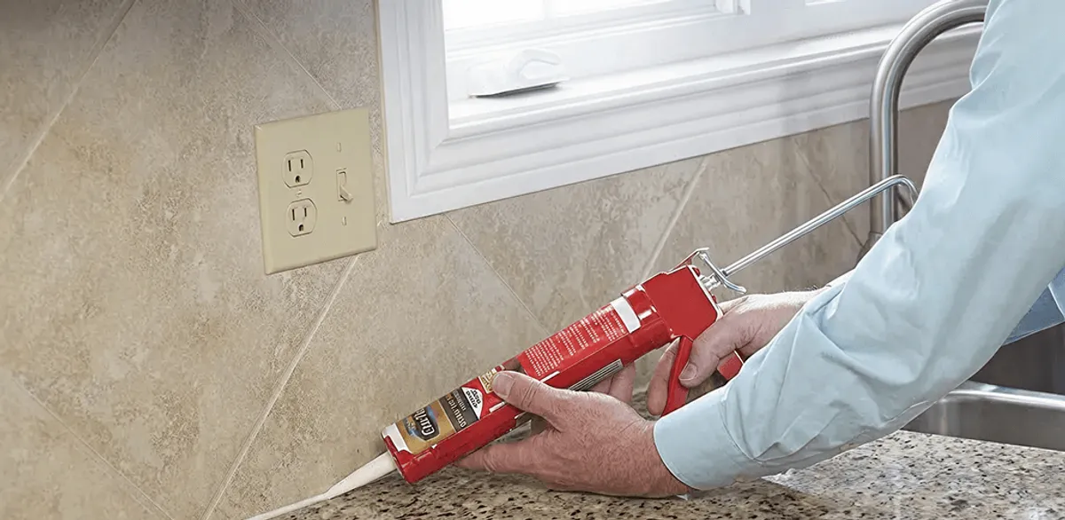 Handyman applying caulk along a kitchen backsplash and countertop seam in Staten Island, NY